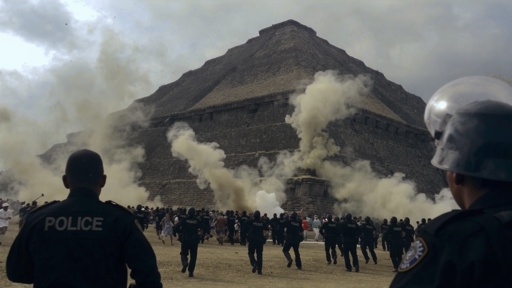 shutterstock_2770166449.jpg Crowd of people running near a pyramid with police officers observing