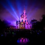 Illuminated Disney castle with colorful lights at night