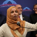 Explosive Al-Qaida Link Haunts OMAR Endorsement… Ilhan Omar speaking passionately at a podium with a group of supporters behind her