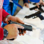 License To Carry? Not To Stop Person holding and inspecting a handgun at display.