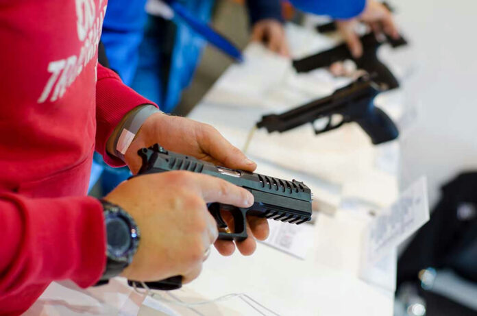 1207070692 Person holding and inspecting a handgun at display.