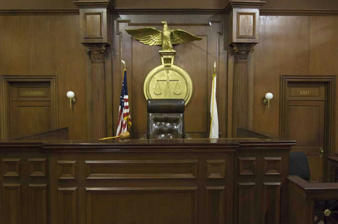 121502698-4 Judges bench in an empty courtroom, scales emblem above.