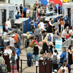 Crowd at an airport security checkpoint with TSA officers.