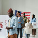 ICE Grabs Voter Data — What’s Missing? People voting in a polling station with American flags.