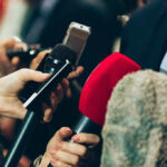 Interview microphones pointed at a person in suit.