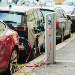 Dealer Panic Torches EV Prices Electric cars charging at street charging stations.