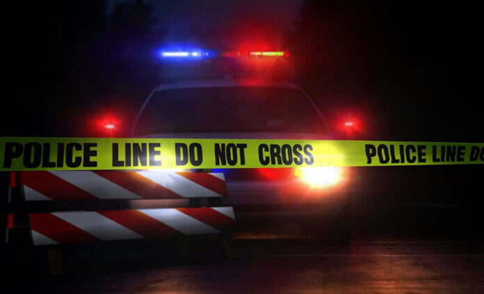 693454099 Police car behind yellow caution tape at night.