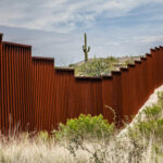 rust-colored border fence in a desert landscape