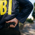 FBI Sniper Ends Bank Standoff FBI agent holding a gun behind the back.
