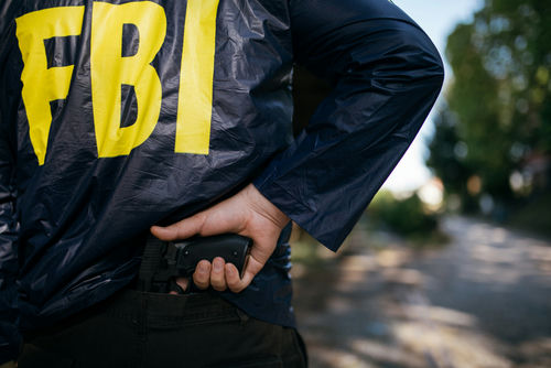 shutterstock624106589-2jpg FBI agent holding a gun behind the back.