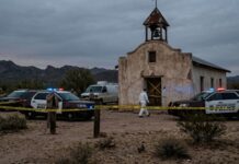 Texas Town Freezes—Shooter Cornered Police vehicles and officers at a crime scene near an abandoned building in a desert area