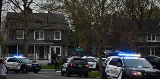 Police vehicles parked outside a house at dusk.