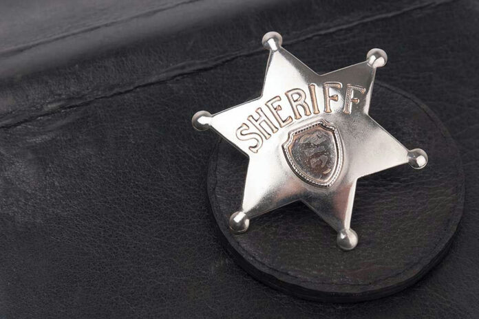 189922118 Sheriff badge on black leather surface.