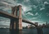 Brooklyn Bridge spanning the East River under dramatic clouds