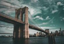 Brooklyn Bridge spanning the East River under dramatic clouds