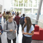 Special Cash Lane For Illegal Immigrants? Students conversing in bright school hallway.
