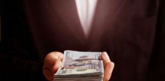 Hand holding a stack of US dollars.