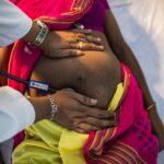 Anchor Baby Panic Sparks Wild Vigilantism A healthcare professional examining a pregnant woman's abdomen with a stethoscope
