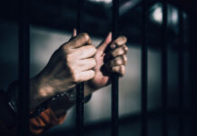 Illegal Trucker, Triple Deaths—Light Sentence? Hands gripping prison bars, suggesting confinement