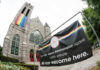 Exterior view of a church with a rainbow flag and an inclusive message banner