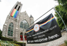 Exterior view of a church with a rainbow flag and an inclusive message banner
