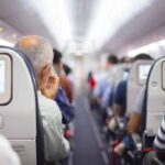 Passengers sitting in airplane seats with screens.