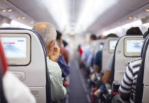 Passengers sitting in airplane seats with screens.