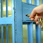 Hand unlocking a metal gate with keys.