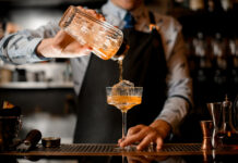 Bartender pouring a cocktail into a glass.