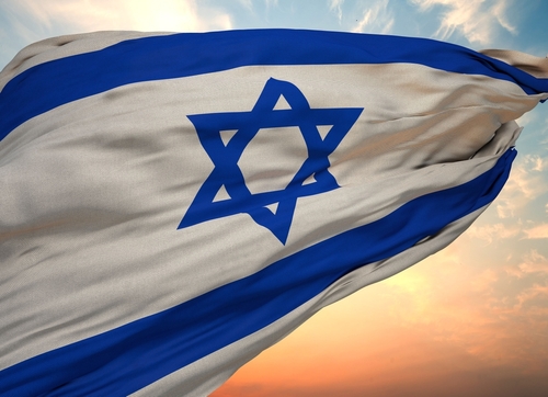 Israeli flag waving against a colorful sunset sky.